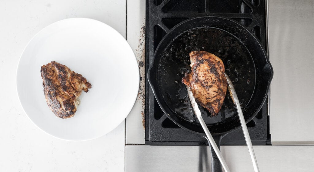 tongs picking up a browned chicken breast