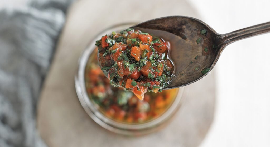 a spoon holding a scoop of red chimichurri sauce