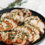 Sliced chicken on a black plate coated in reverse marinade