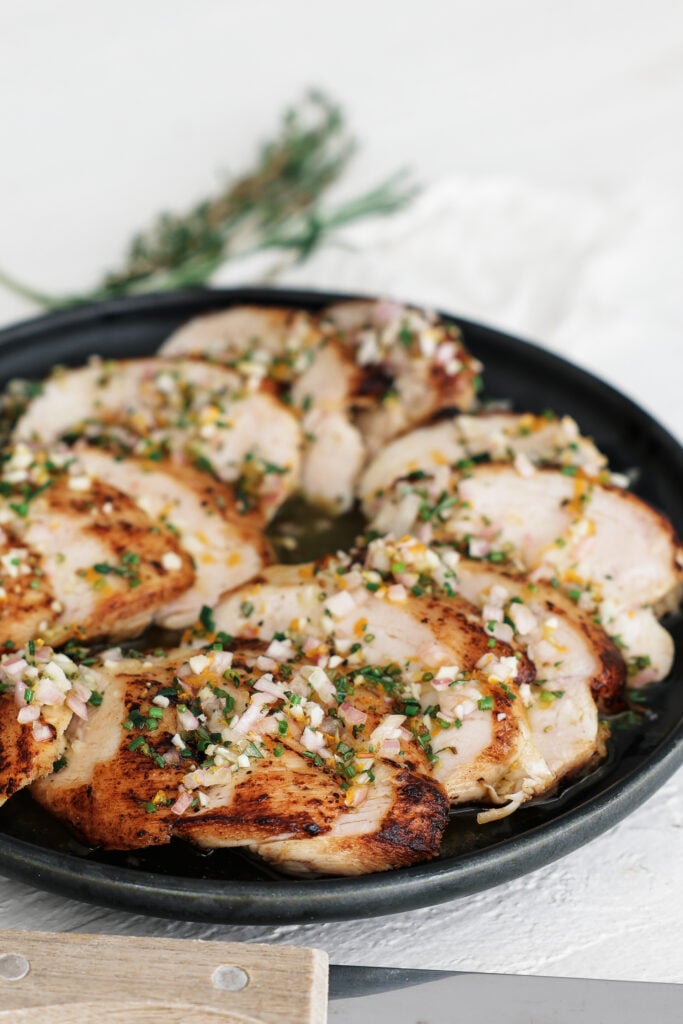 Sliced chicken on a black plate coated in reverse marinade
