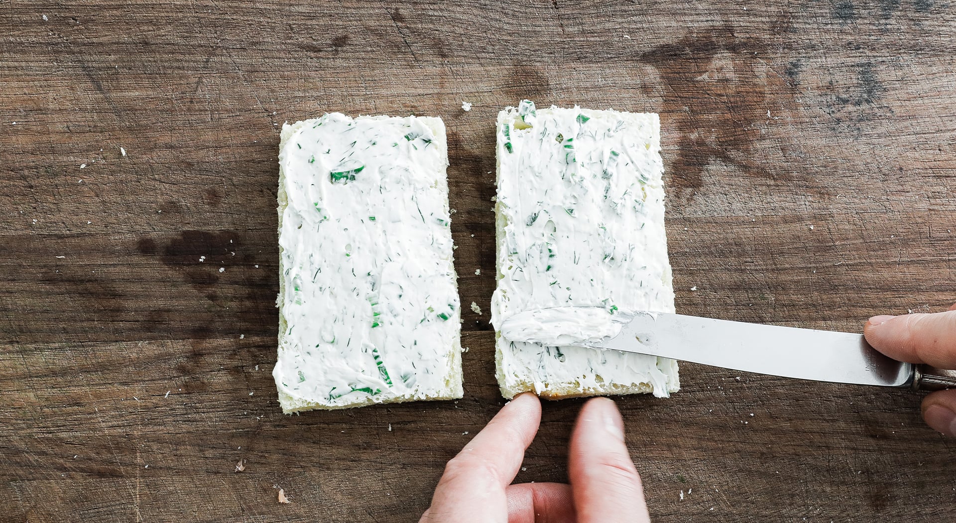 spreading cream cheese on bread