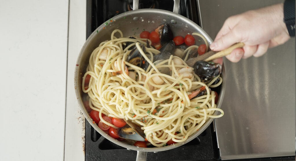 folding cherry tomatoes into pasta with seafood