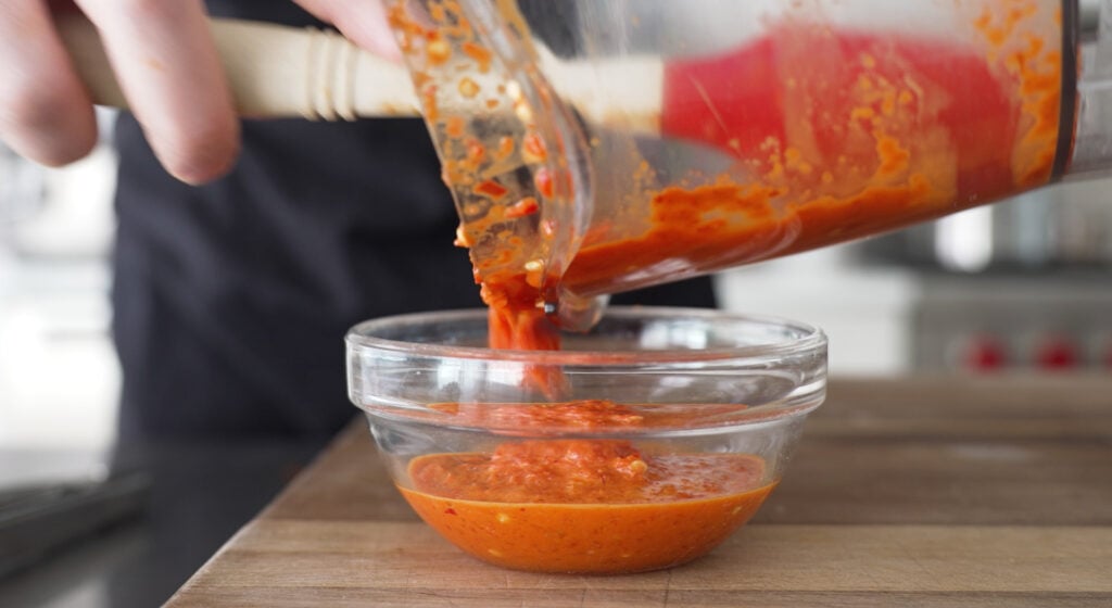 pouring sauce from the immersion blender into a glass bowl