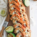 Shrimp skewers on a cutting board with lime halves around