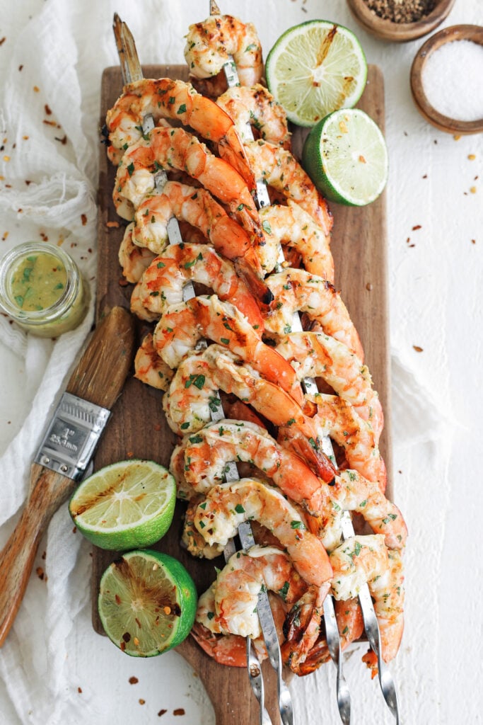 Shrimp skewers on a cutting board with lime halves around