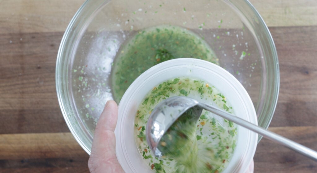 taking a small ladle of marinade out of the large bowl