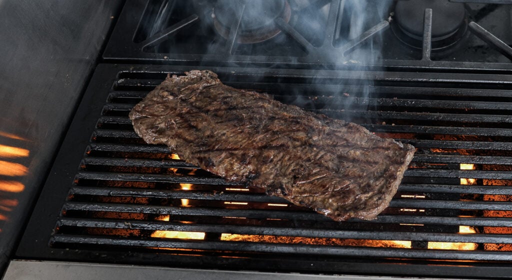 Skirt steak on a hot grill with flames under the grates