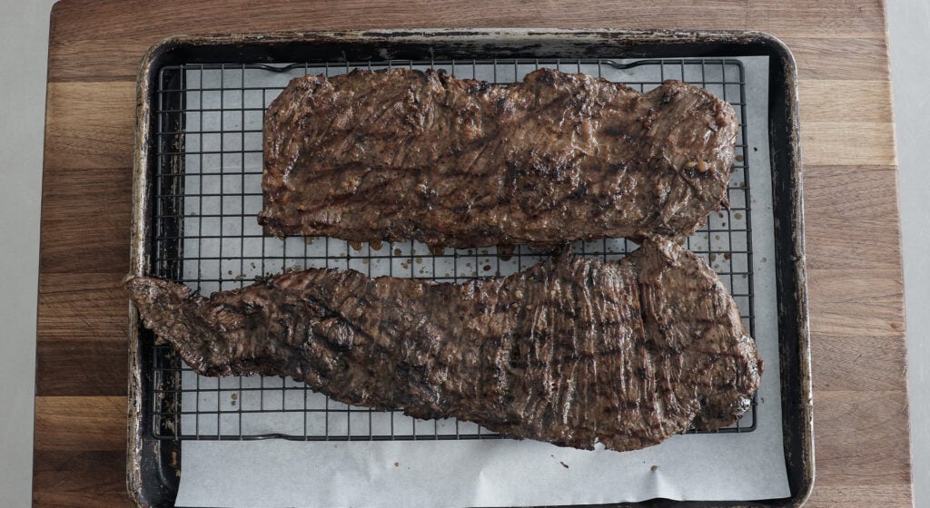 grilled skirt steak resting on a sheet tray 