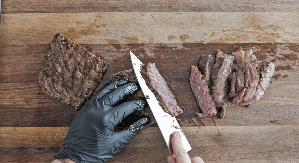 slicing the skirt steak on a wooden cutting board