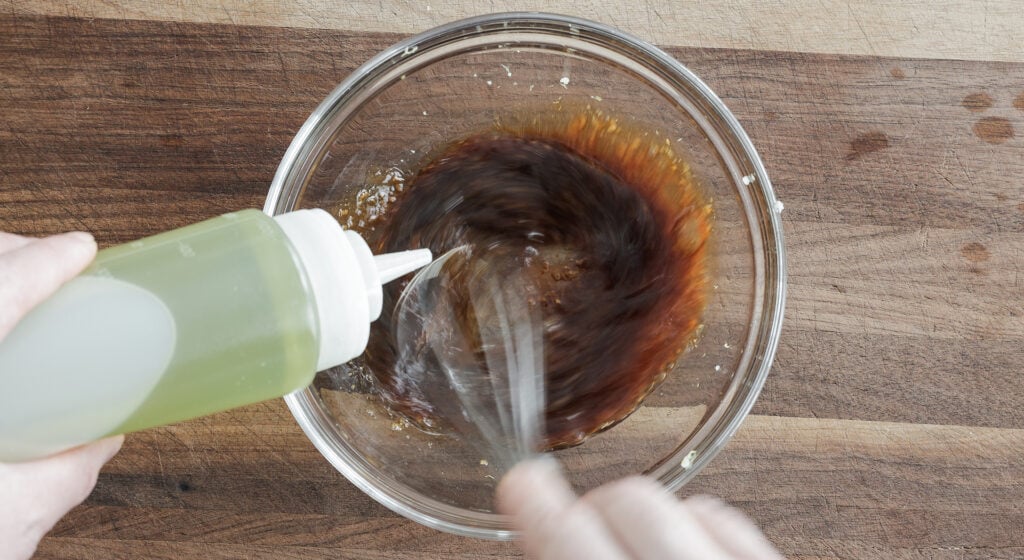 drissling oil into bowl and whisking to combine