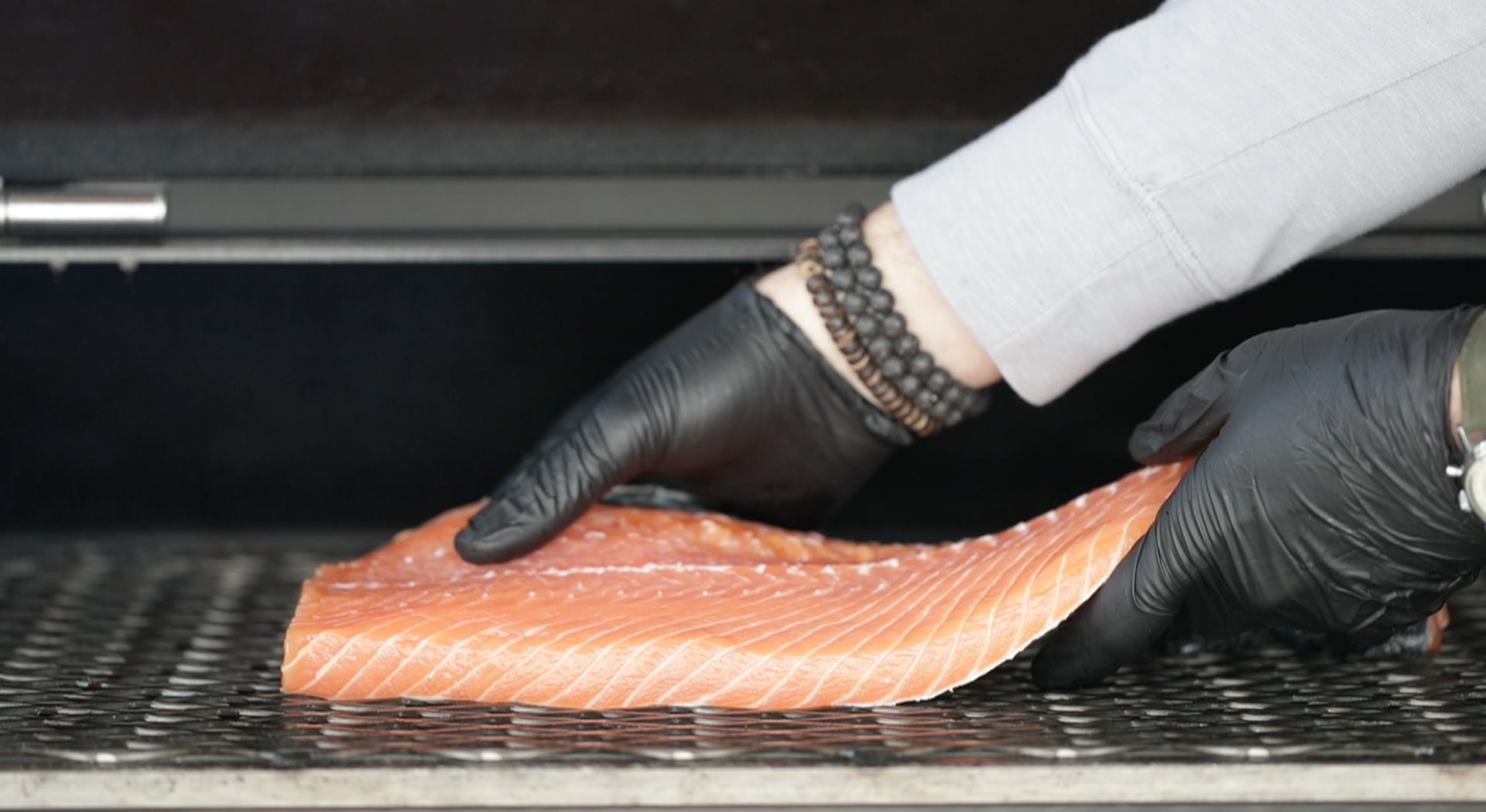 adding a salmon onto a smoker