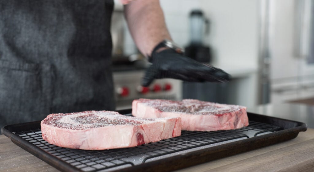 salted Steak on a rack over a sheet tray