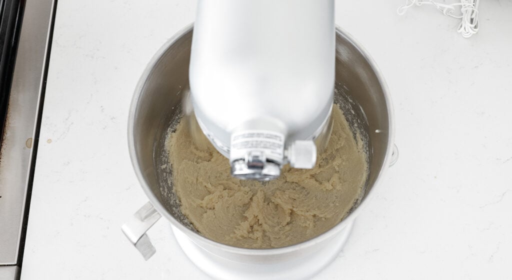 A stand mixer with creamed butter in the bowl