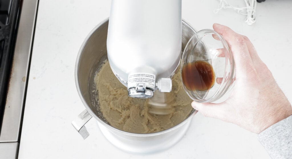 pouring vanilla into the bowl of a stand mixer