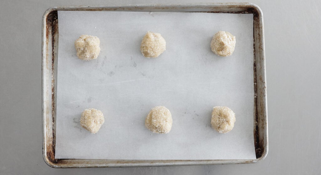 6 balls of dough on a sheet lined with parchment paper