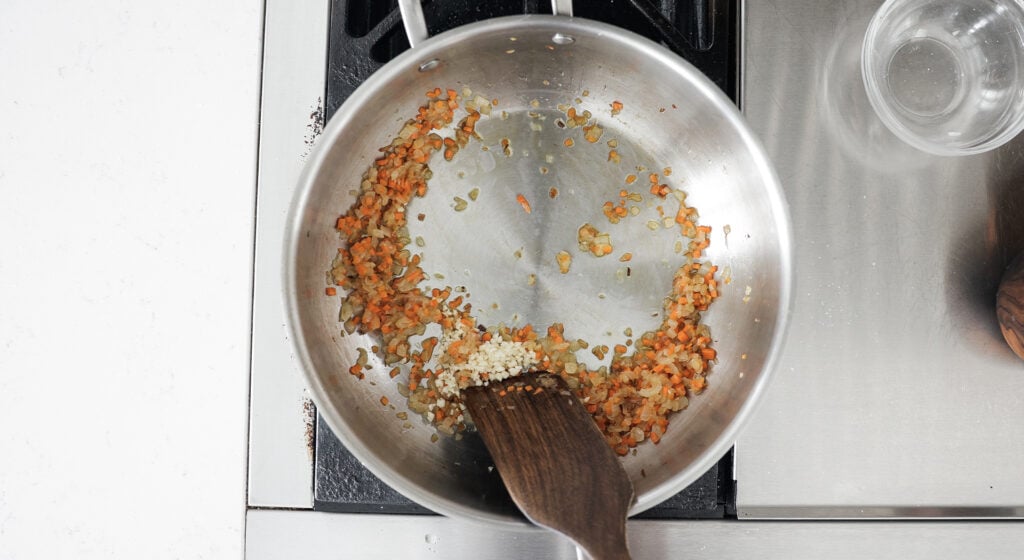 Cooking garlic and carrots in a pot with onions
