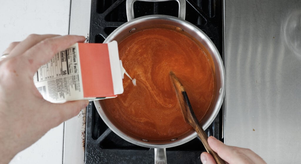 stirring heavy cream into the pot of soup