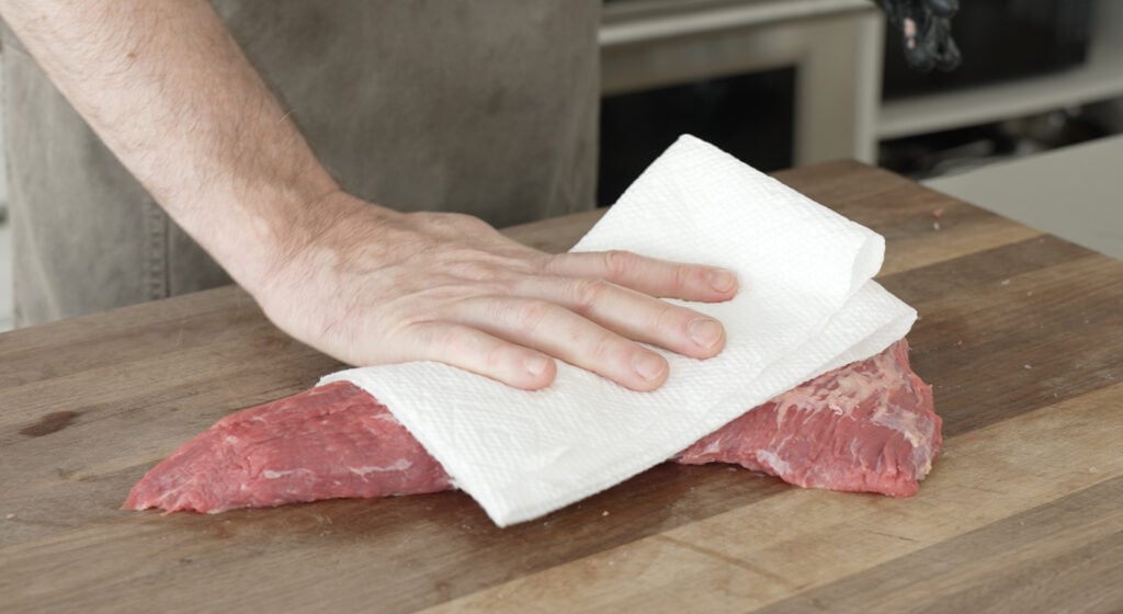 Using a paper towl to pat the steak dry