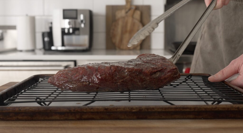 placing a seared steak on a wire rack