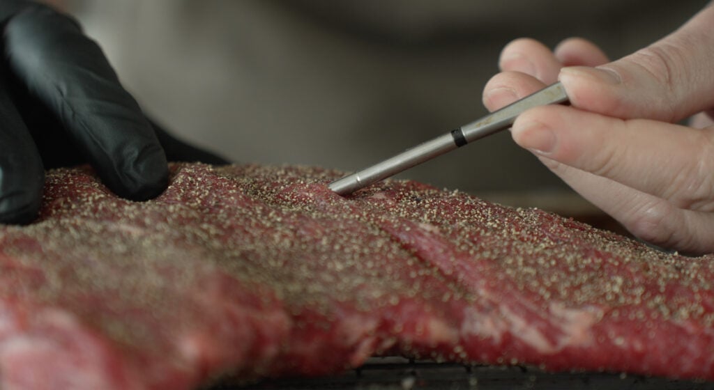 A thermometer being placed in a steak