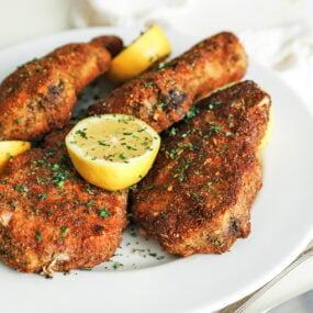 plate of cooked breaded pork chops with lemons