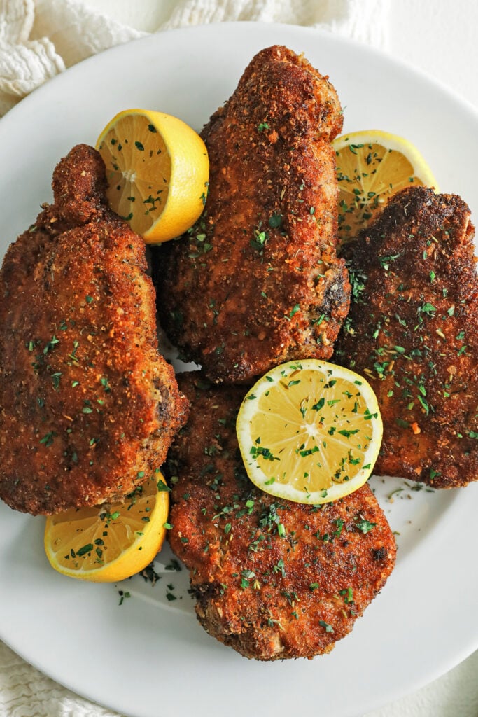 plate of cooked breaded pork chops with lemons