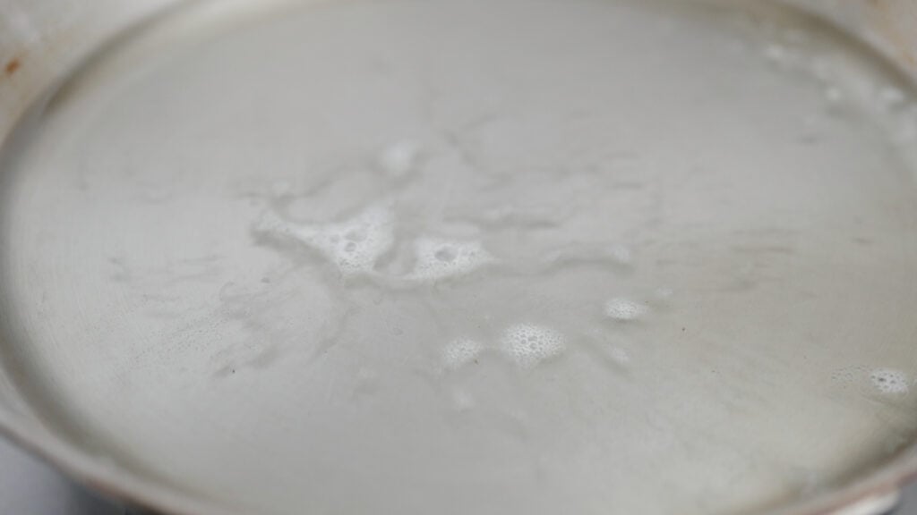 testing hot oil with bread crumbs in a pan
