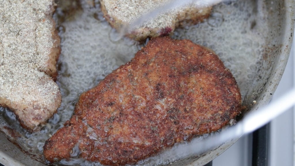 frying a breaded pork chop in a pan