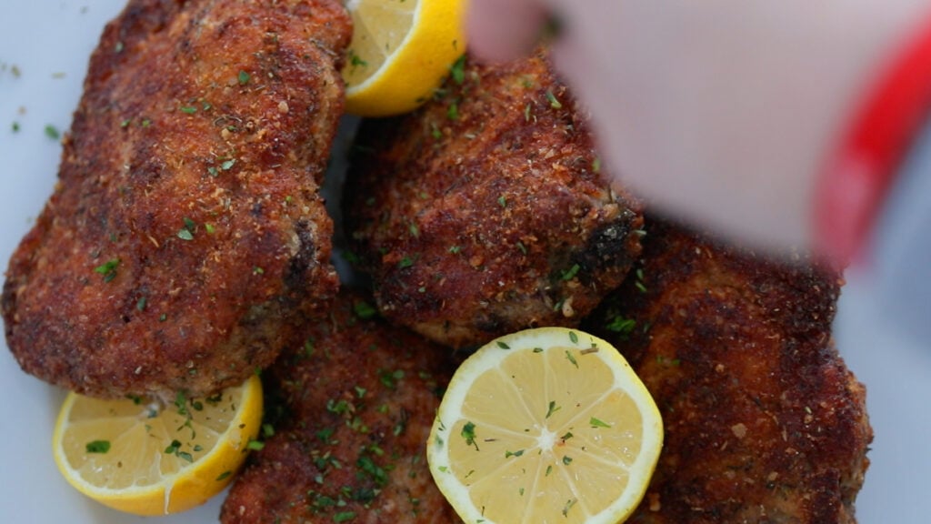 serving some breaded pork chops with lemons and parsley