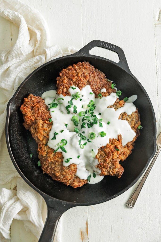cast iron skillet with chicken fried steak and gravy