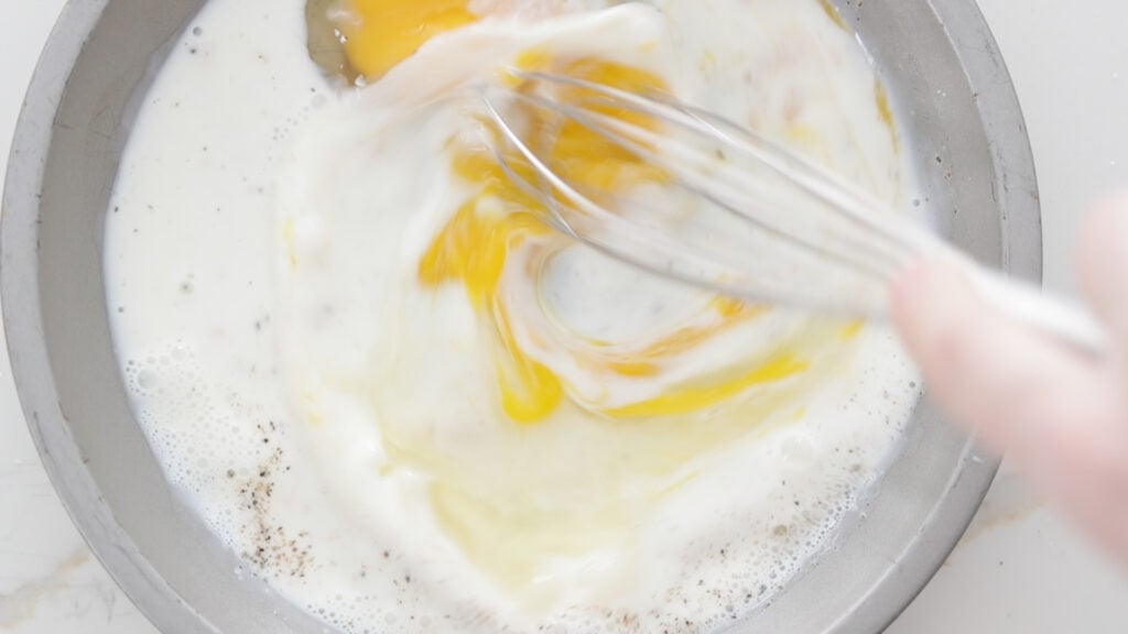 whisking together eggs and milk in a pan