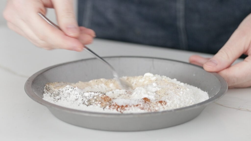 mixing flour and spices in a pan with a fork