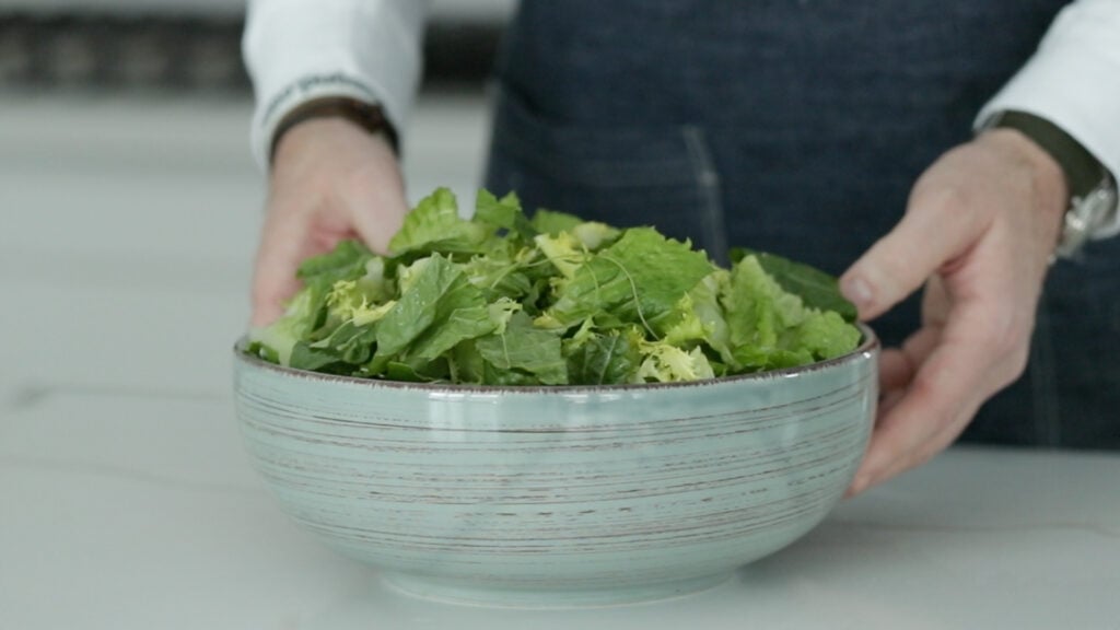 adding lettuces to a large bowl