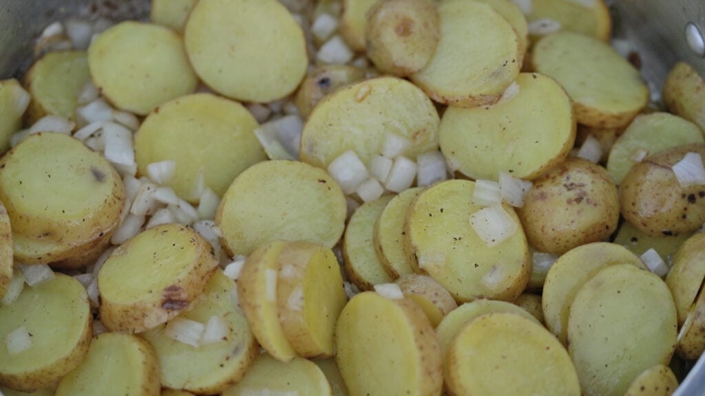 cooking sliced potatoes and onions in a pan