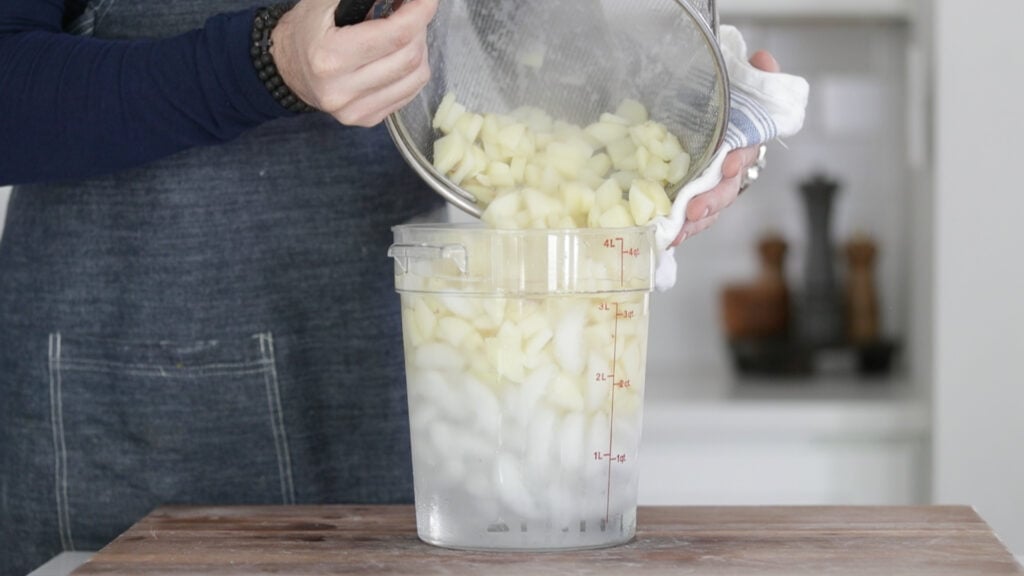 adding boiled potatoes to a container full of ice water