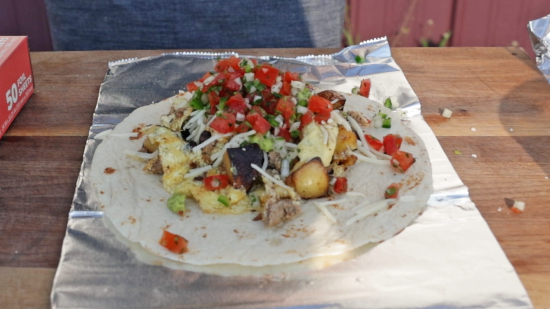 adding salsa and guacamole to a breakfast burrito