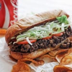Chopped cheese with potato chips and pickle spears on the side