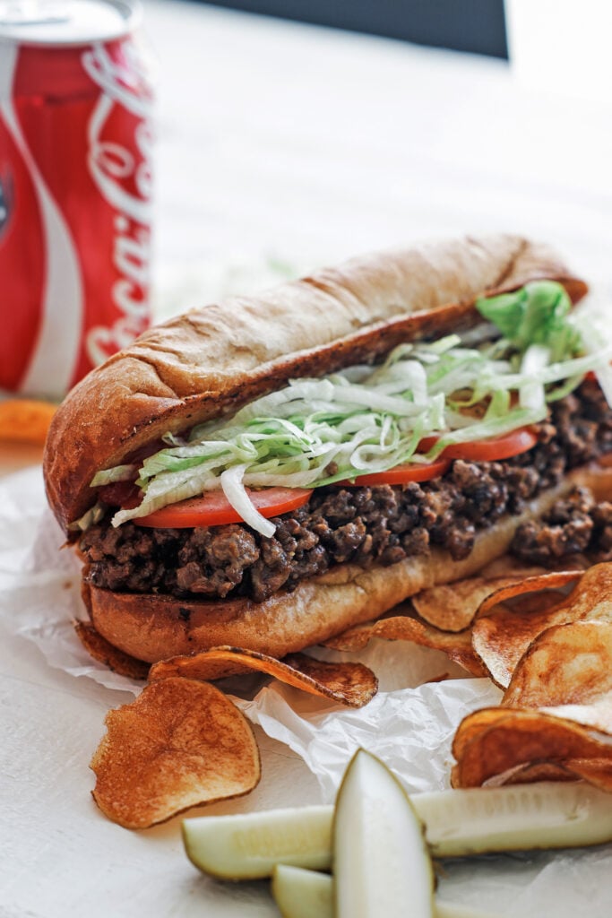 Chopped cheese with potato chips and pickle spears on the side