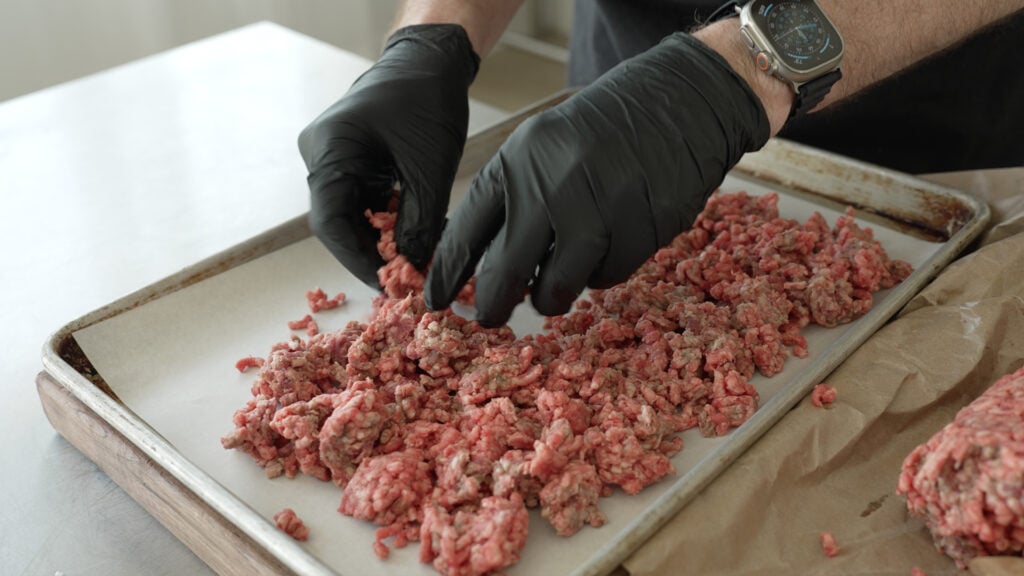 Laying ground beef out on a sheet tray
