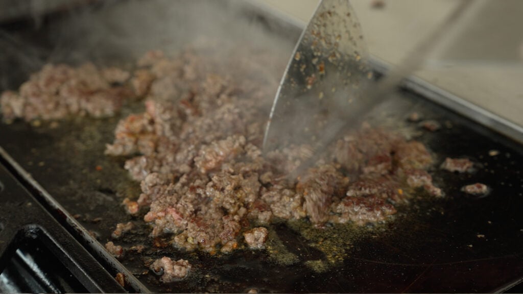 Steaming browned ground beef on a griddle
