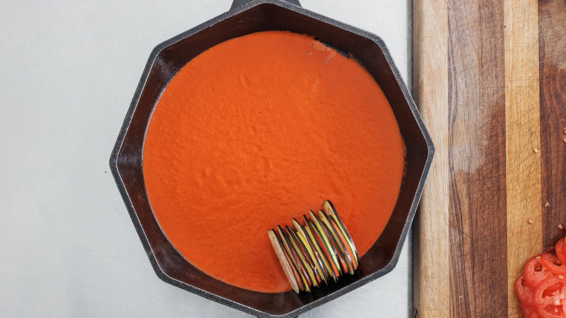 adding vegetables to a skillet with sauce