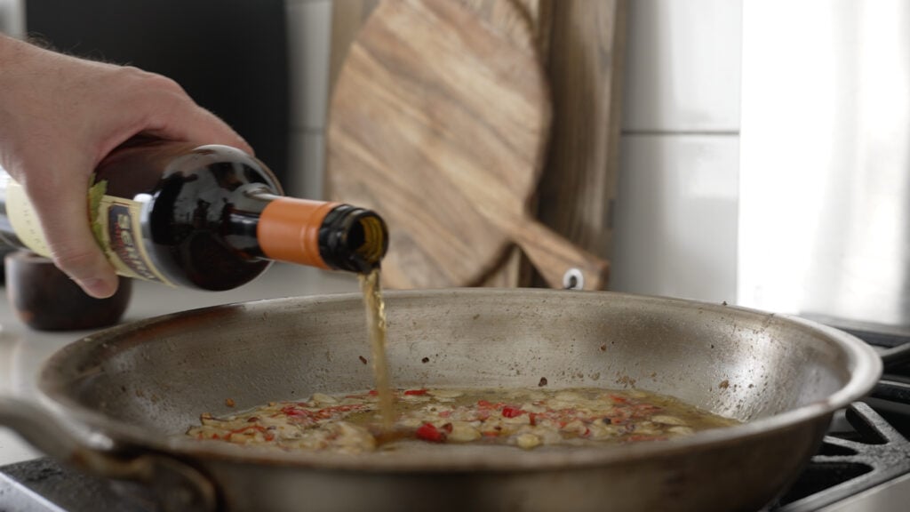 pouring the sherry into the pan with garlic and peppers
