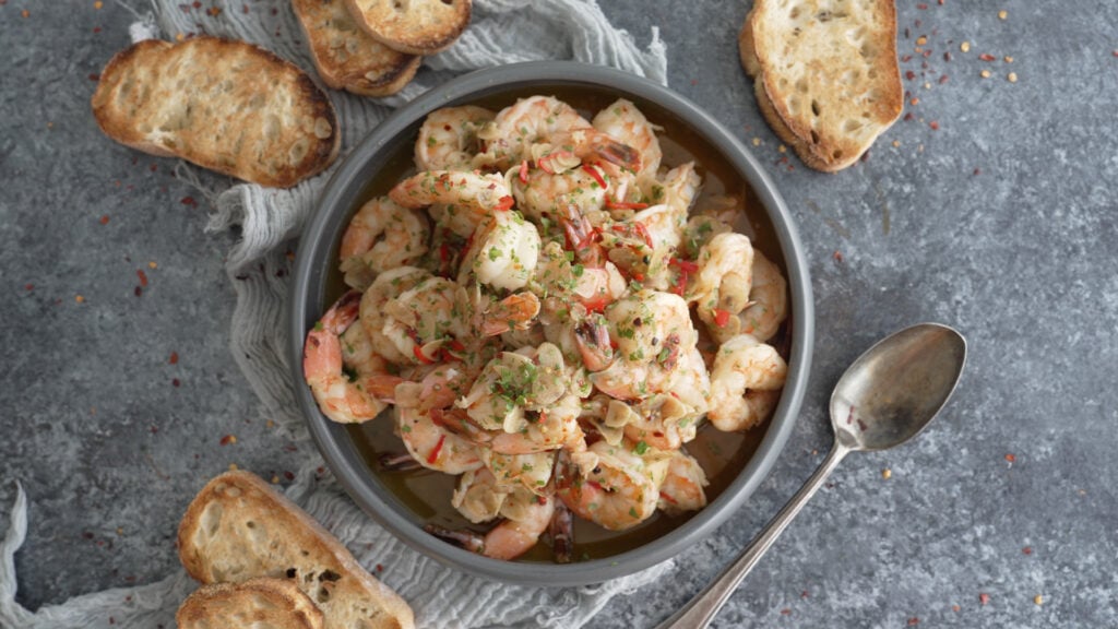 finished bowl of gambas al ajillo with crusty bread on the side