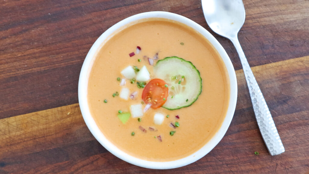 Gazpacho served in a bowl with fresh toppings.