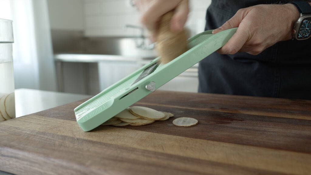Using a mandoline to slice a potato