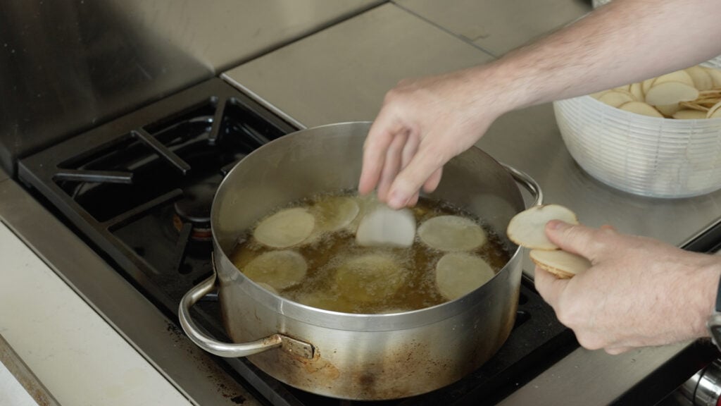 placing potato slices in the oil one at a time