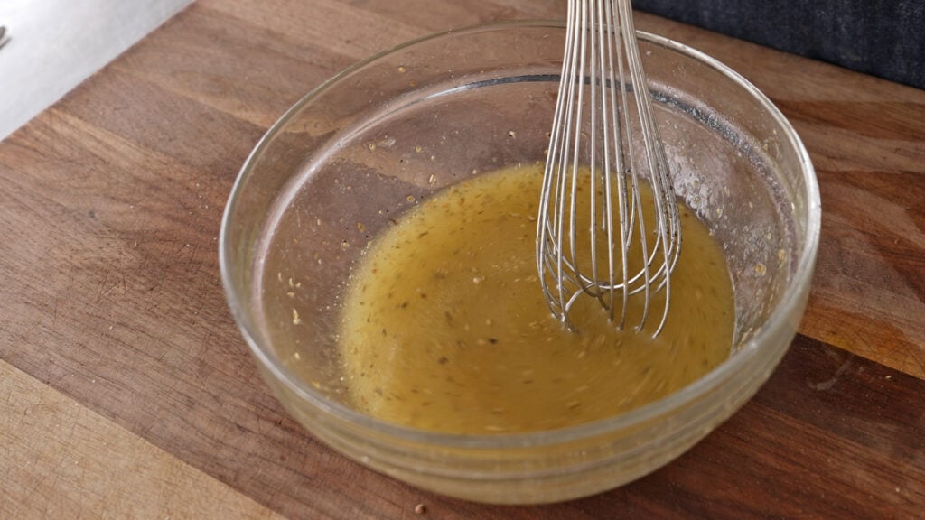 whisking the vinaigrette in a bowl