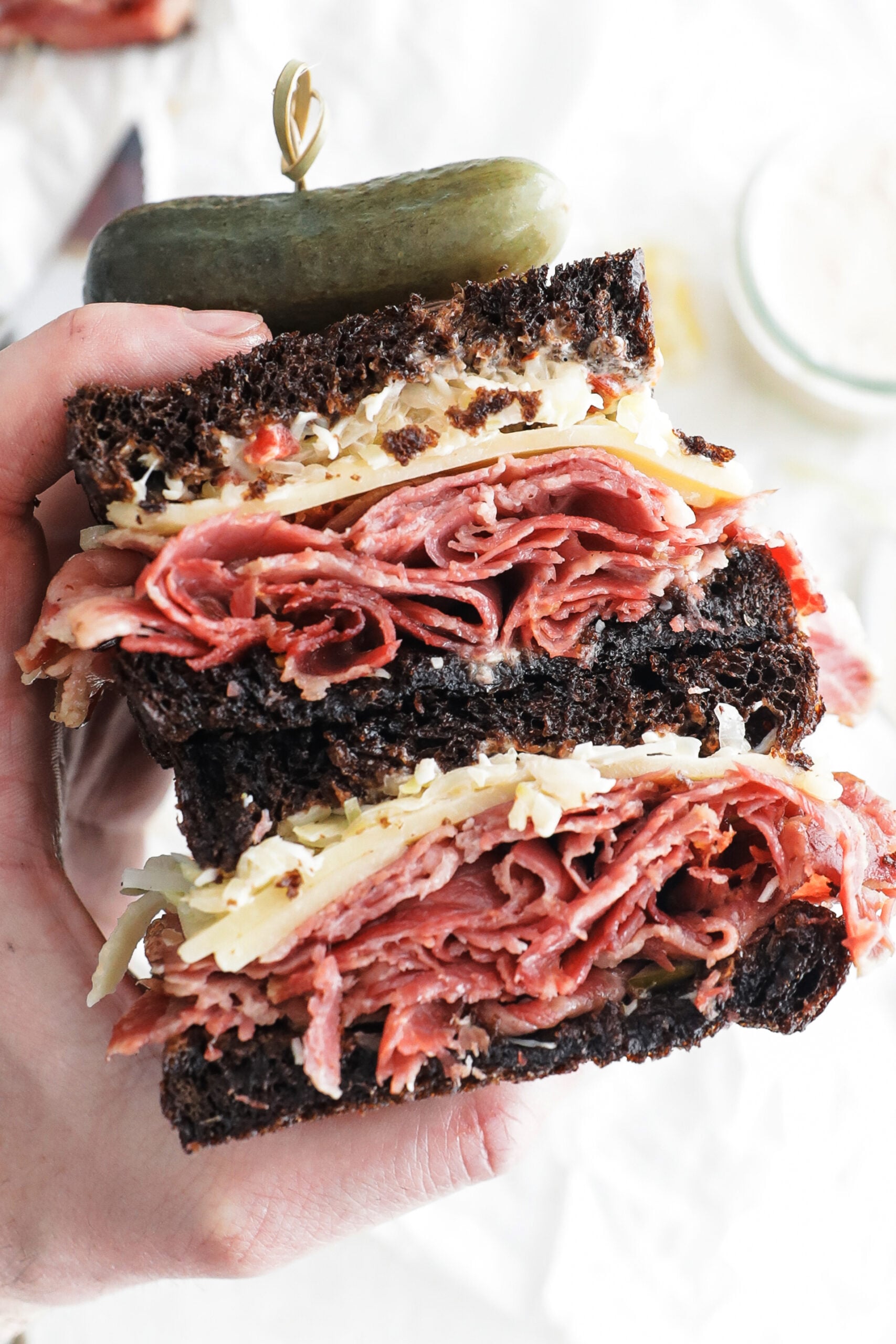 holding a sliced reuben sandwich