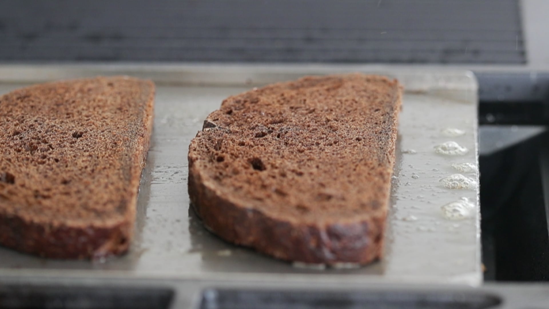 toasting some pumpernickel bread on a flat top