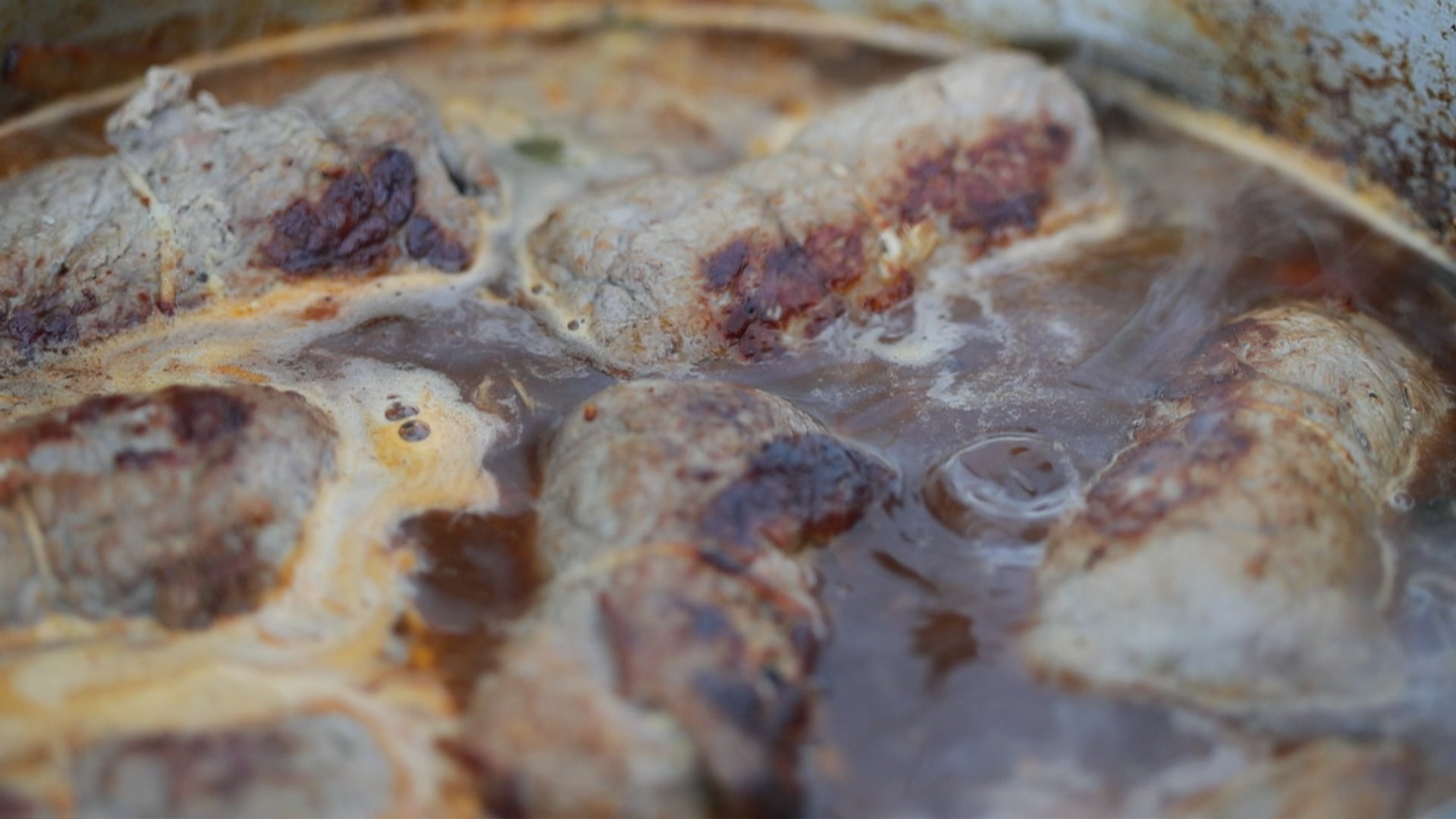 adding seared beef into a braising pan with beef stock